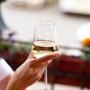 Frauenhand hält ein Glas Weißwein