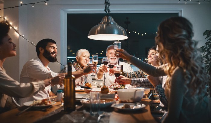 Frohe Runde stößt bei einem weihnachtlichen Abendessen mit alkoholfreien Getränken an, um die besinnliche Zeit zu feiern