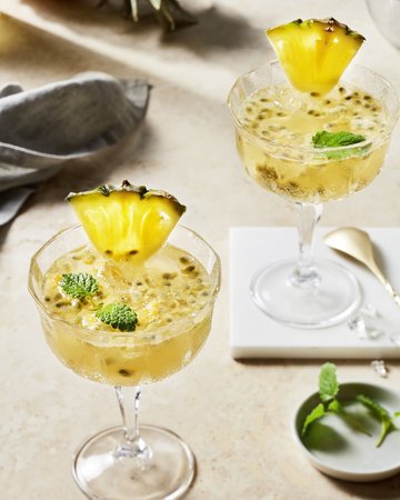 Exotischer Cocktail mit Passionsfrucht, garniert mit einer Ananasscheibe und Minzblatt, ideal für tropische Sommerabende