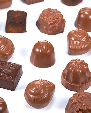 Eine Vielfalt von handgefertigten Schokoladenpralinen mit verschiedenen Füllungen und Verzierungen, kunstvoll arrangiert