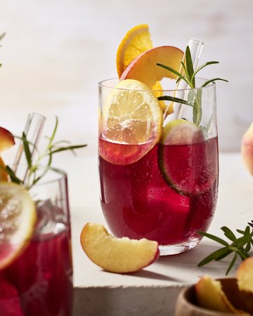 Ein Glas voller Sangria ohne Alkohol, garniert mit Zitrusfrüchten und Rosmarin, ein erfrischendes Getränk für gesellige Anlässe