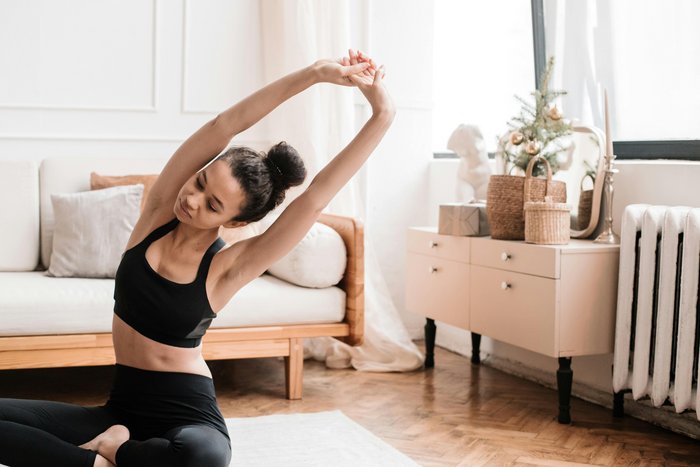 Eine junge Frau praktiziert Yoga zu Hause als Teil einer gesunden Lebensweise ohne Alkohol
