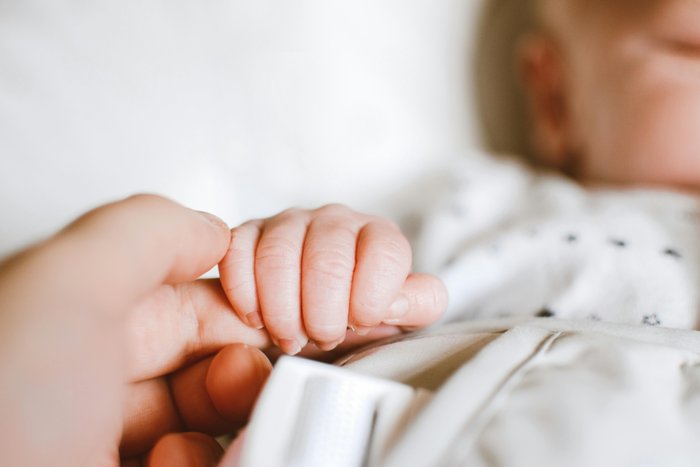 Neugeborenes hält den Finger einer Erwachsenen, symbolisch für die Bedeutung einer sicheren und gesunden Bindung, welche durch Alkoholverzicht während der Stillzeit unterstützt wird